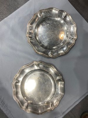 Deux cendriers en métal plaqué argent sont posés sur une table