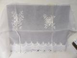 a white table cloth with white flowers on it and a pair of scissors next to it