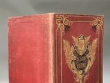an old book with a red cover sitting on top of a table