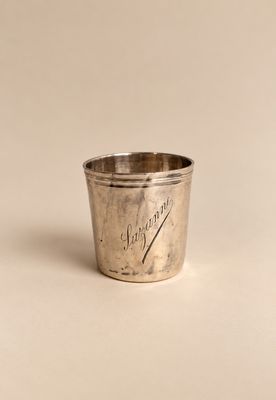 une vieille coupe en argent posée sur une surface blanche