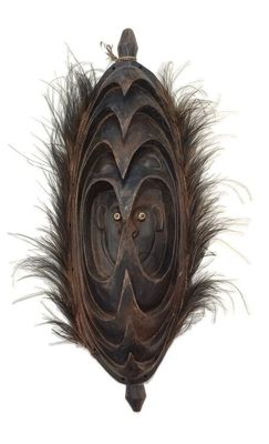 an image of a wooden mask with feathers on a white background