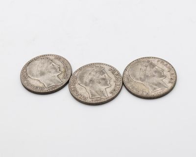 trois pièces d'argent posées l'une à côté de l'autre sur une surface blanche