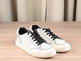 white sneakers with black laces on a wooden surface