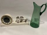 un pichet en verre vert et une horloge posés sur une table blanche