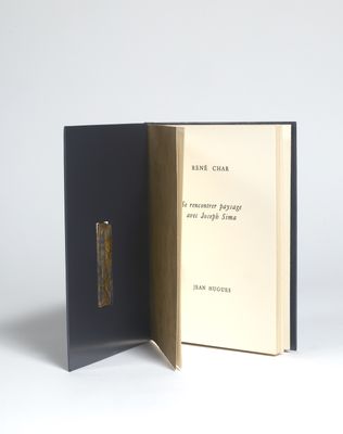 un livre ouvert posé sur une table à côté d'un mur blanc