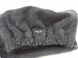 a black hat with a button on it on a white surface