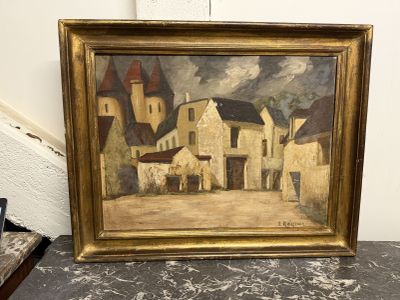 une peinture à l'huile représentant une scène de village, dans un cadre doré, posée sur une table