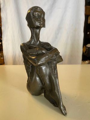 sculpture en bronze représentant une femme assise sur une table