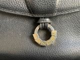 the handle of a black purse with a gold ring on it