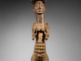 une statue en bois d'un homme avec un chapeau sur la tête