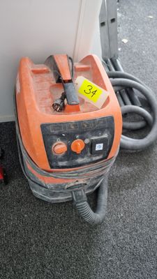 an orange machine that is sitting on the floor next to a wall