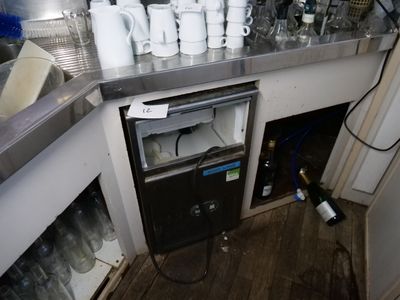un petit réfrigérateur dans un coin de la cuisine, sur lequel sont posées de nombreuses tasses
