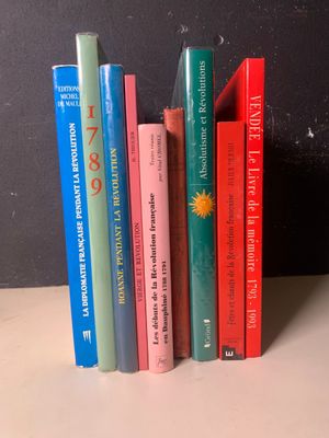 Plusieurs livres sont alignés sur une étagère devant un mur noir