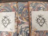 two old books with designs on them sitting on a table