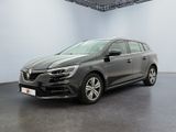Une voiture grise est garée dans une pièce blanche au sol noir.