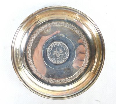une assiette en argent sur laquelle figure le portrait d'une personne
