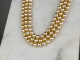 a close up of a necklace with pearls on a marble surface