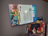 a pile of comic books on a shelf next to a piano