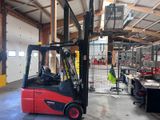 un chariot élévateur rouge dans un grand entrepôt où il y a beaucoup de travail