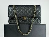 a black chanel bag with a gold chain on top