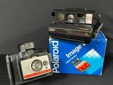 a polaroid camera sitting on top of a box next to a polaroid camera