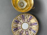 a close up of a gold cup and saucer on a table