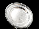 une assiette en argent posée sur un support, sur une surface noire