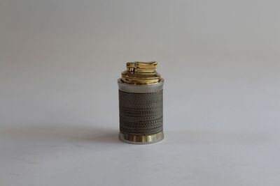 a small silver and gold lighter sitting on a white surface