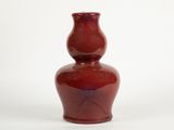 a red vase that is sitting on a white surface