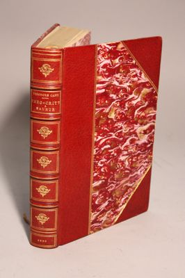 an old red book with gold trim sitting on top of a white surface