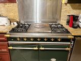 a green stove in the middle of a kitchen with many utensils on it