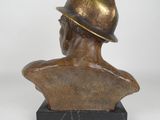 bronze bust of a man wearing a hat on a marble base