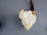 a pipe with a carved head on it next to other items