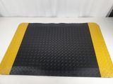 a black and yellow diamond plate mat on a white surface