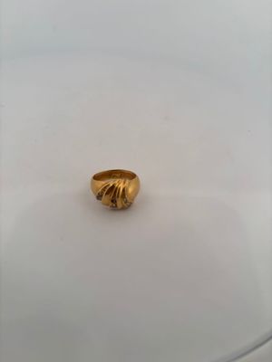 a close up of a gold ring sitting on top of a white surface