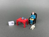a miniature figurine of a man sitting at a table with a cat