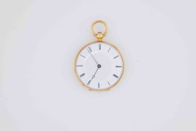 a gold pocket watch with a white face on a white surface