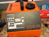 une machine orange et noire posée sur une table, à côté d'autres outils