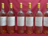 six bouteilles de vin sont alignées les unes à côté des autres sur un fond rouge