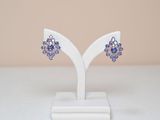 boucles d'oreilles en cristal violet posées sur un support blanc, sur une surface blanche
