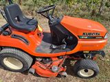 an orange riding lawn mower sitting on top of a grass covered field