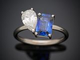 un gros plan d'une bague sertie d'un diamant et d'un saphir sur une surface noire