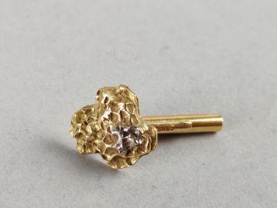 a close up of a small gold flower on a white surface