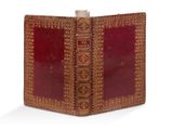 un vieux livre à la couverture rouge posé sur une surface blanche