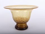 vase en verre jaune posé sur un socle en bois, sur fond blanc, avec un fond blanc