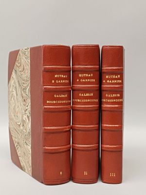 three red books sitting on top of each other on a white surface