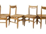 four wooden chairs sitting next to each other on a white surface