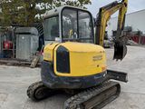 the back end of a yellow and black excavator parked in a parking lot
