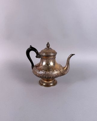 une vieille théière en argent avec une anse noire sur un fond blanc