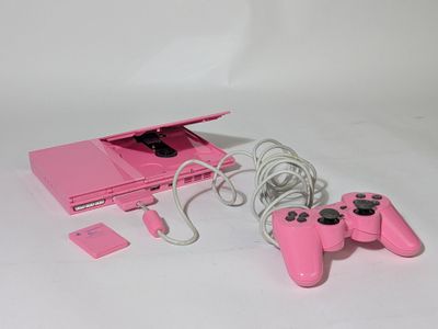 une console de jeux vidéo rose avec deux manettes et un chargeur